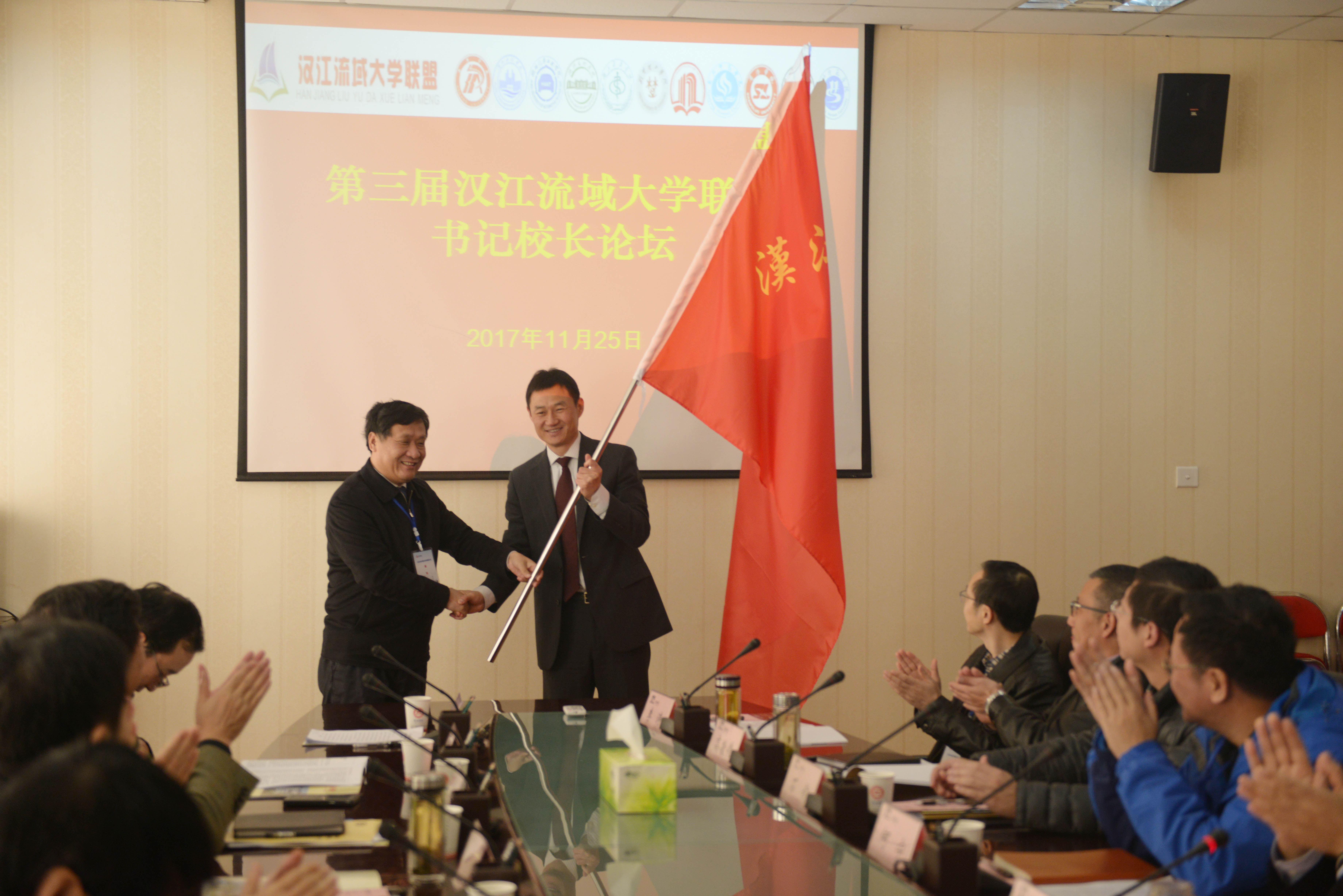 2党委书记黄荣杰代表2017年轮值理事长单位向2018年轮值理事长单位商洛学院授旗.JPG