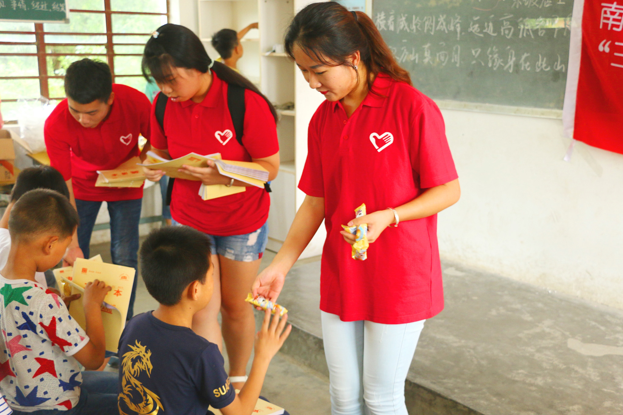 2志愿者在给同学们发放礼物.jpg